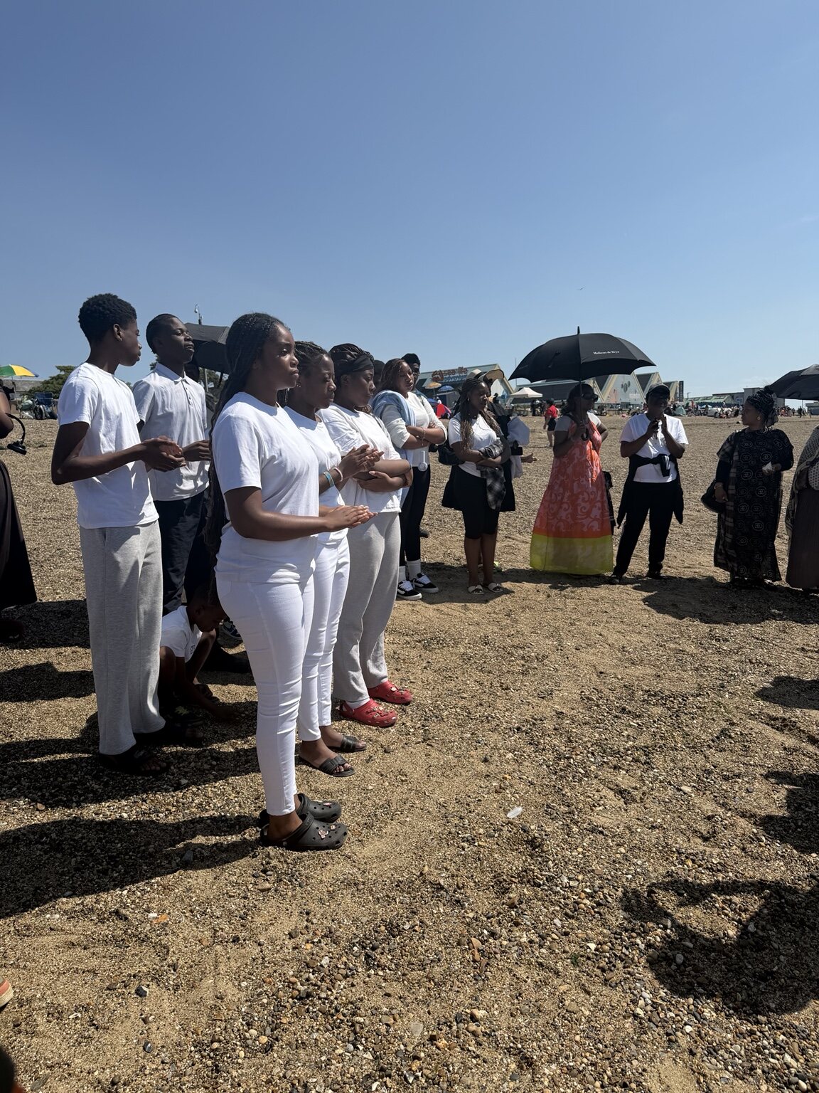 Baptism candidates and church members gathered in prayer on the beach